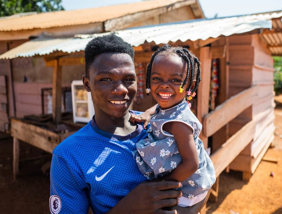 Smiling person holding a young child in Accra, Ghana.