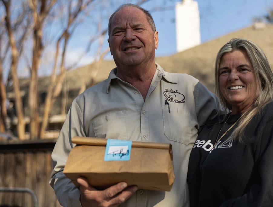 Couple smiling outside their home in Rowlett holding a delivery package.