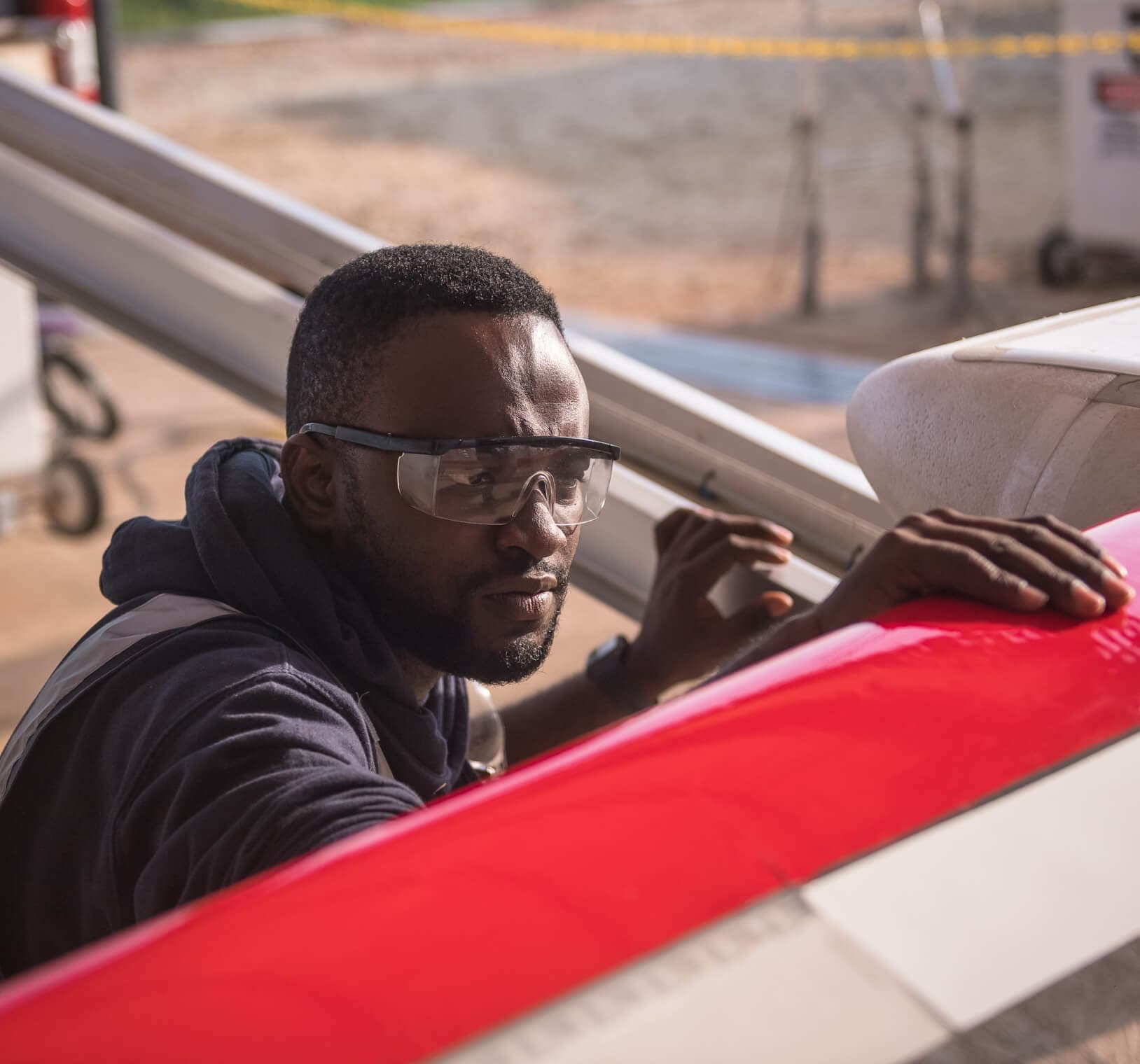 Person wearing safety glasses inspecting a drone wing outdoors.