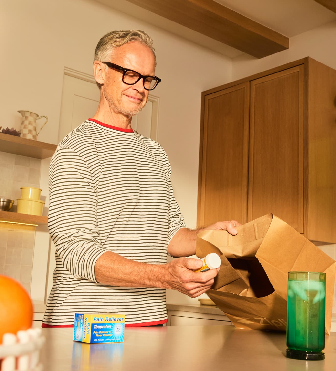Person unpacking medication from a delivery bag in a kitchen.
