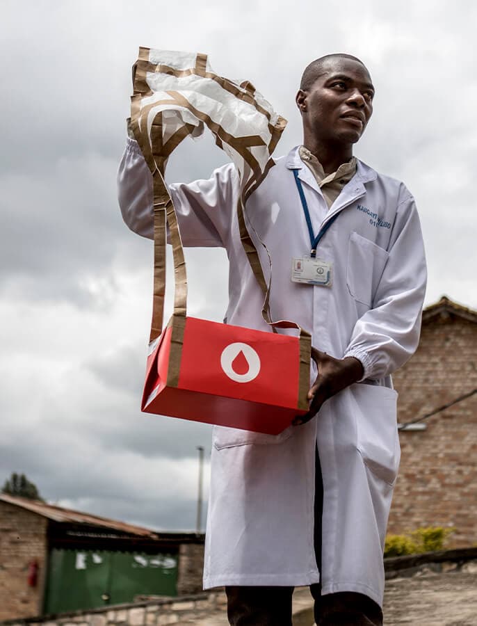 Healthcare worker holding a parachute delivery package outdoors.