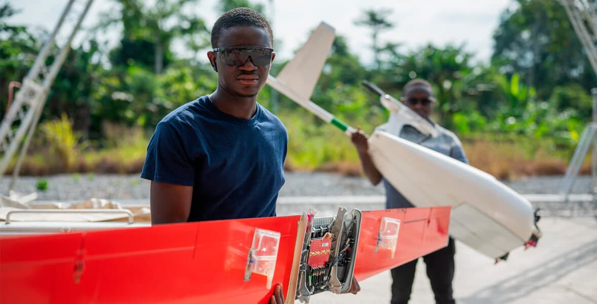 Two people handling a Zipline drone wing outdoors.