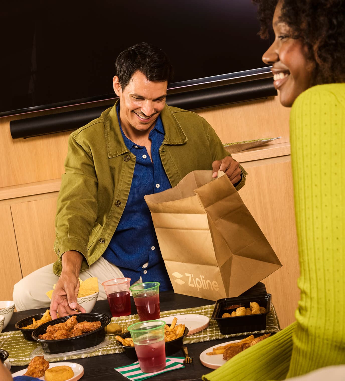 Two people unpacking a Zipline delivery bag at a table with food.