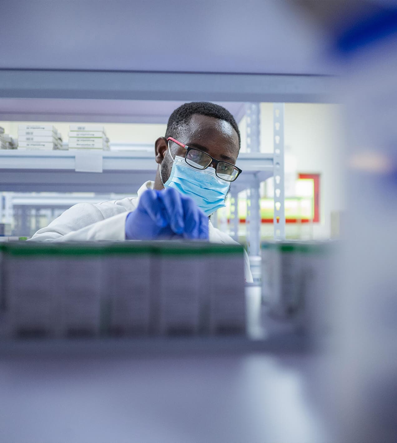 Healthcare worker in mask and gloves handling medical supplies in a fulfillment hub.