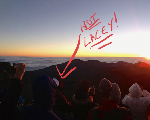 Tourists enjoying the Haleakala National Park sunrise. The text "NOT LACEY" is scribbled on the image with an arrow pointing to one of the travelers. 